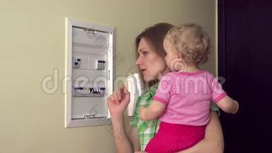 女人带着婴儿在手臂检查断<strong>路</strong>器电器<strong>回家</strong>。 4K